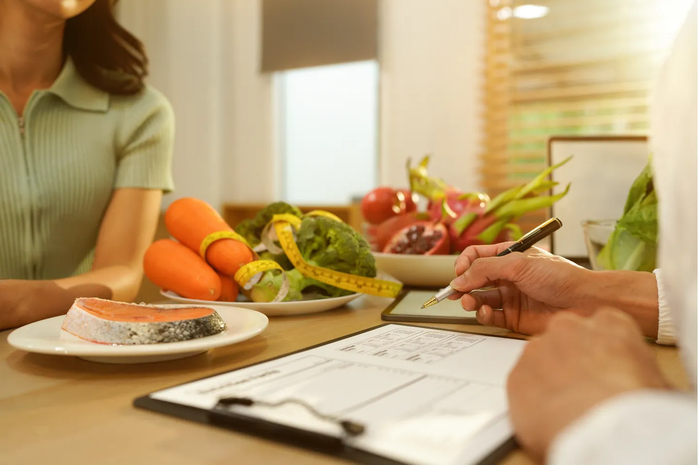 A nutritionist consults with a client, surrounded by fresh vegetables and a plate of salmon.